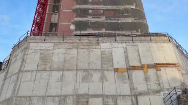 Yapım aşamasında olan uzun, modern bir bina, vinçler ve iskeleler, mimari tasarım sergileniyor.