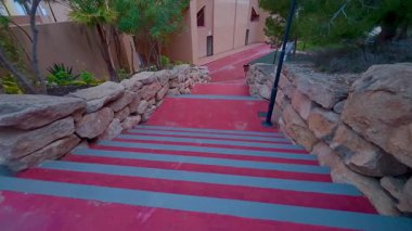 Çok güzel dizayn edilmiş kırmızı merdiven seti göz kamaştırıcı taş aksanlarıyla peyzajlı bir alanda süzülüyor.
