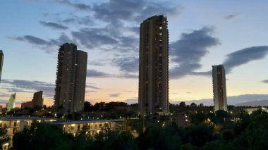 Renkli bir alaca karanlık gökyüzüne karşı modern aydınlık kulelerin yer aldığı bir şehrin nefes kesen manzarası..