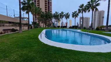 Yüksek palmiye ağaçları ve modern binalarla dolu güzel bir havuz. Rahatlamak ve rahatlamak için mükemmel.