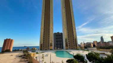 Huzurlu ve davetkar bir havuz manzarasının yanında modern mimari bir tasarıma sahip görkemli ikiz gökdelenler.