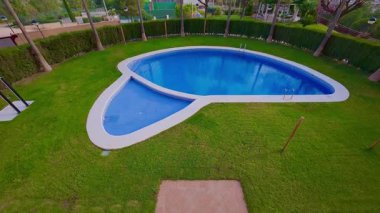 Göz kamaştırıcı bir havuz tasarımı canlı otlar ve sallanan palmiye ağaçları ile çevrilidir, rahatlatıcı bir açık hava alanı yaratır.