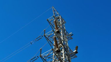Elektrik iletimi için parlak mavi gökyüzü altında yüksek bir yapı. Mühendislik harikaları sergiliyor..