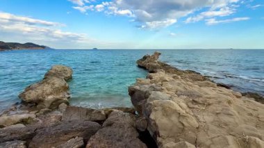 Berrak suları ve gökyüzünün huzur dolu sükunetiyle kayalık bir sahil şeridinin nefes kesici güzelliğini hissedin.