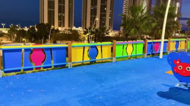 Renkli yapıların ve çocukların eğlenmesi için tasarlanmış çeşitli ekipmanların yer aldığı canlı bir oyun alanı.