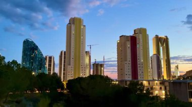 Şok edici bir şehir manzarası alacakaranlıkta gökyüzü, güzel aydınlanmış binalar ve canlı bulutlar sergiliyor..