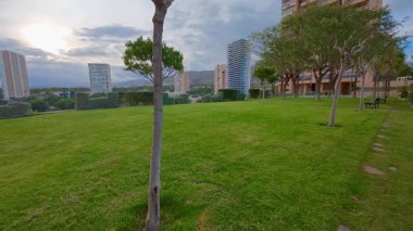 Gün batımında modern çağdaş binalarla birlikte bereketli, canlı yeşillikler sergilenen huzurlu ve sakin bir açık hava.