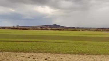 Bulutlu gökyüzünün altındaki yeşil alanların sakin görüntüsü güzelliği ve sükuneti takdir etmek için mükemmel.