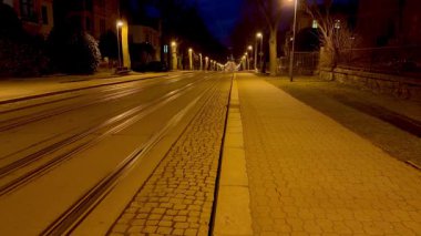 Boş tramvay rayları, sokak ışıklarının sıcacık parıltısıyla yıkanmış, geceleri huzurlu bir atmosfer yaratıyor.