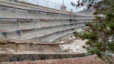 İnşaat halindeki bir istinat duvarının detaylı bir görüntüsü, yapı iskelesi ve kayalık bir çevre..