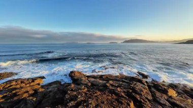 Güneşin doğuşunda kayalık kıyılara çarpan dalgaların nefes kesici görüntüsü, doğanın huzurunu yakalıyor..