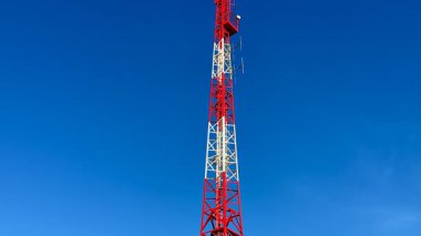 Çarpıcı bir iletişim kulesi yukarıdaki açık ve parlak mavi gökyüzüne karşı uzun ve görkemli duruyor.