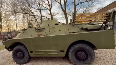 Bu fotoğraf, sakin ve barışçıl bir açık hava ortamında çekilmiş eski bir yeşil askeri aracın yan görüntüsünü gösteriyor.