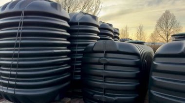 Çok sayıda siyah su tankı bir araya toplanmış, dayanıklı tasarımlarını güzel bir günbatımına karşı sergiliyorlar..