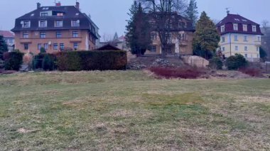 Huzurlu ve pitoresk bir manzara cazibesiyle tarihi evleri sergiliyor bulutlu bir gökyüzünün altında sergilenen sakin bir çim tarlası.