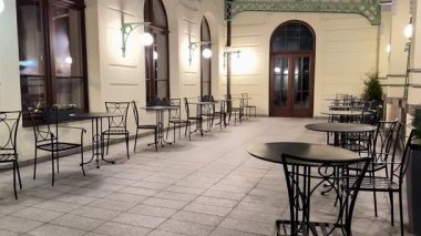Konforlu gece manzarasında boş kafeterya masaları var. Yumuşak aydınlatılmış, davetkar atmosferi arttıran.