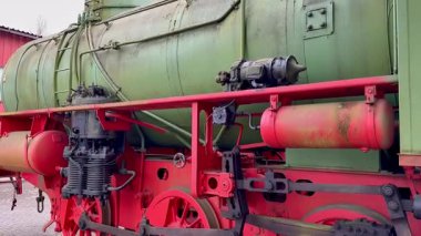 Eski bir buharlı lokomotifin karmaşık ve detaylı görüntüsü canlı ve renkli makinelerini gururla sergiliyor.