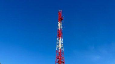 Parlak mavi gökyüzüne karşı modern iletişim teknolojisini temsil eden uzun ve sağlam bir telekom kulesi.
