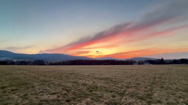 Nefes kesici ve çarpıcı bir günbatımı engin açık araziler ve uzak dağlar üzerine canlı ve parlak renkler döküyor.