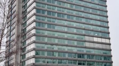 Çağdaş bir ofis binasının parlak ve modern cephesi şehir ortamında göze çarpıyor.