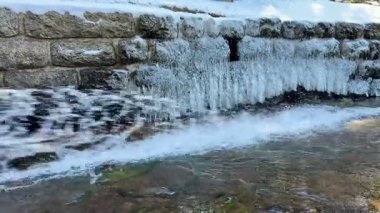 Sakin ve sakin bir kış nehri nefes kesici buz oluşumları sergiliyor kıyıları güzelce kaplıyor.
