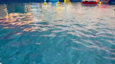 Gün batımında rengarenk şamandıralar ve dalgalı suyla aydınlatılmış güzel bir havuz. Yaz temaları için mükemmel.