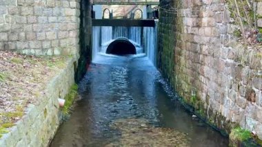 Güzel, taşlaşmış bir drenaj kanalından süzülen huzurlu ve huzurlu bir su manzarası.