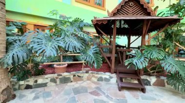 Bereketli tropikal bitkilerle çevrili ahşap bir çardağı olan sakin bir kapalı alan davetkar atmosferini arttırıyor.