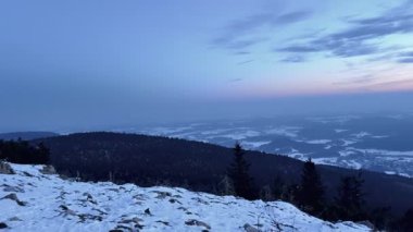 Huzurlu ve sakin bir kış manzarası. Güzelce sergilenen karla kaplı alacakaranlık gökyüzünün altındaki görkemli dağlar.