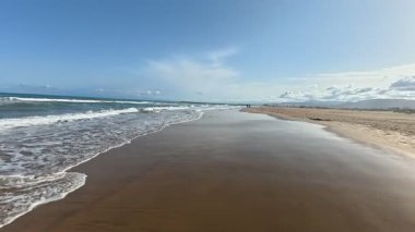 Sakin bir sahil sahnesi hayal edin yumuşak altın kumları ve parlak bir gökyüzünün altında yumuşak okyanus dalgalarını