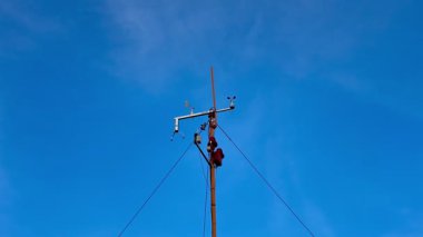 Çok yetenekli bir teknisyen parlak mavi gökyüzüne karşı bir elektrik direği üzerinde gerekli bakım işlerini yapar.