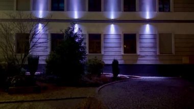 Mimari zarafet ve ambiyans sergileyen, geceleri güzelce aydınlatılmış modern bir bina cephesi..