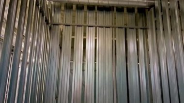 Dikey metal levhalar içeren boş bir metal depolama kabını gösteren bir iç görünüm