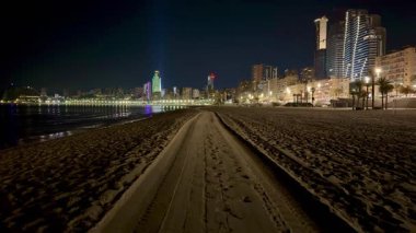 Geceleri nefes kesici bir sahil manzarası, göz kamaştırıcı şehir ışıkları ve canlı bir gece hayatı ortamı.