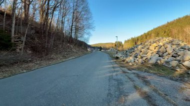 Bereketli ormanlık tepeler ve kayalık arazilerle çevrili dolambaçlı bir yolun huzurlu ve sakin bir manzarası.