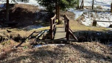 Sakin, karlı bir ormanda yuva yapmış küçük, tuhaf bir ahşap köprü, onu sakin kış yürüyüşleri için mükemmel kılıyor.