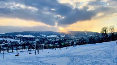 Huzurlu ve sakin bir kış manzarası. Karlı bir manzaranın üzerinde muhteşem bir gün batımı sergiliyor.