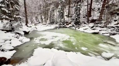 Karla kaplı kayalar ve uzun ağaçların yer aldığı inanılmaz sakin bir kış nehri sahnesi, gerçek güzellikleri gözler önüne seriyor.