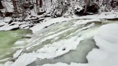 Şelalesi ve karlı ormanı olan donmuş dağ nehri. Doğanın sesi. Yüksek kalite 4k görüntü