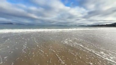 Sakin bir sahil sahnesi yumuşak dalgalar ve dramatik bir akşam gökyüzü, rahatlamak ve gevşemek için ideal.