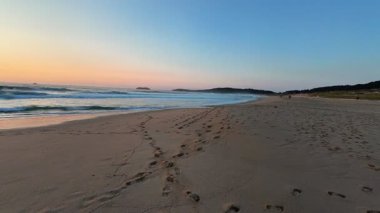 Güzel ve dingin bir sahil sahnesi, dalgalar sergiliyor kıyıya vuruyor ve nefes kesici bir gün batımı.