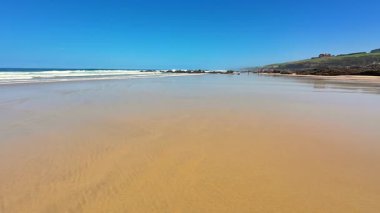 Güzel, sakin bir sahil manzarası altın kumu, kristal gökyüzünü ve yumuşak, yatıştırıcı dalgaları sergiliyor.