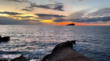 Nefes kesici bir günbatımı ön planda kayalarla okyanusu aydınlatıyor, doğanın güzelliklerini yakalıyor..