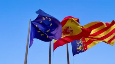 Avrupa Birliği ve İspanyol ulusal bayrakları parlak mavi gökyüzünün altında gururla sallanıyor.