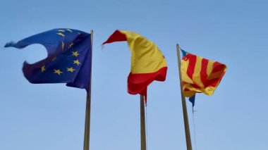 Avrupa, İspanya ve Katalonya 'nın renkli bayrakları güzel bir meltemle mavi gökyüzüne doğru dalgalanıyor.
