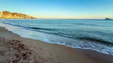 Huzurlu ve güzel bir sahil manzarası sakin dalgalar usulca çarpıyor ve okyanusun üzerinde resim gibi bir gün batımı.