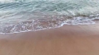 Gün batımında kumlu kıyıya usulca çarpan yumuşak dalgaların dinginliğine ve dinginliğine dalın.