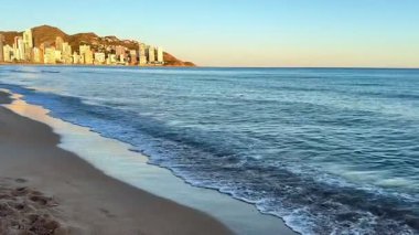 Huzurlu bir sahil sahnesini keşfetmek için bir dakikanızı ayırın. Huzurlu dalgalar ve çarpıcı, canlı günbatımı renkleri.