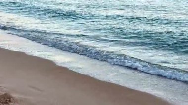 Yumuşak dalgaların sakin bir sahnesi. Güzel kumlu bir kumsalda hafifçe süzülüyor. Mükemmel bir rahatlama için.