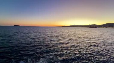 Sakin okyanus sularının üzerinde güzel bir günbatımı, canlı renkler ve manzaralı bir kıyı şeridi..